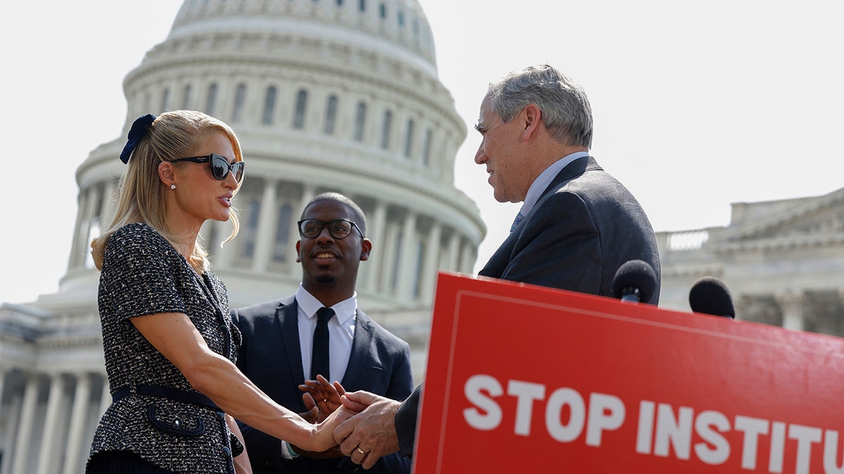 Paris Hilton shaking hands with a man outside Capitol Hill.