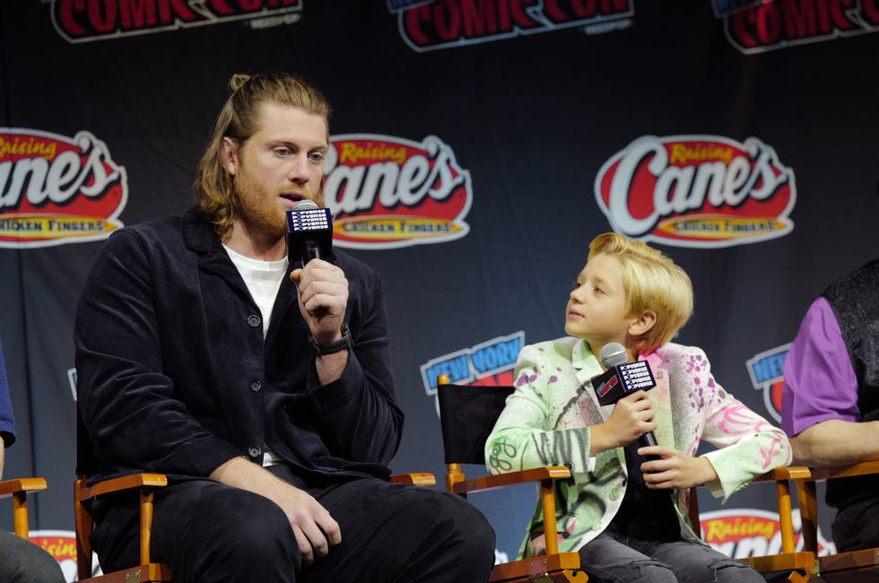 man and teenager sitting in chairs and looking at each other as they speak into microphones