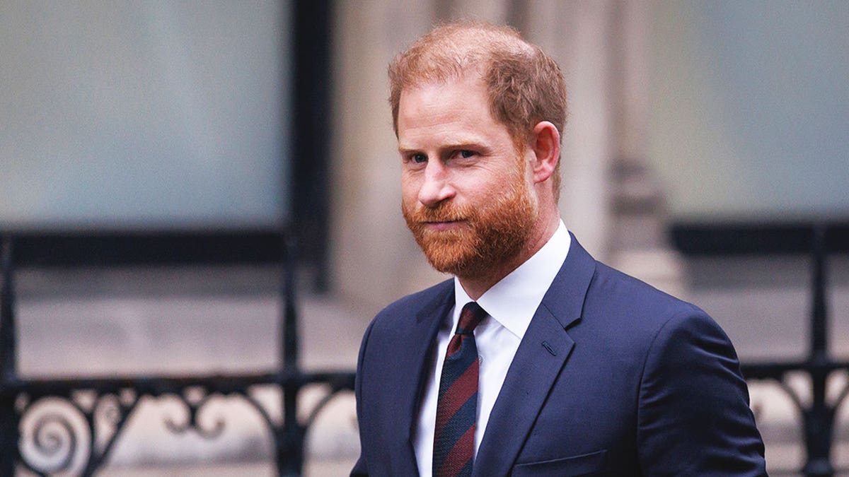 A close-up of Prince Harry walking to the courtroom in a dark blue suit.