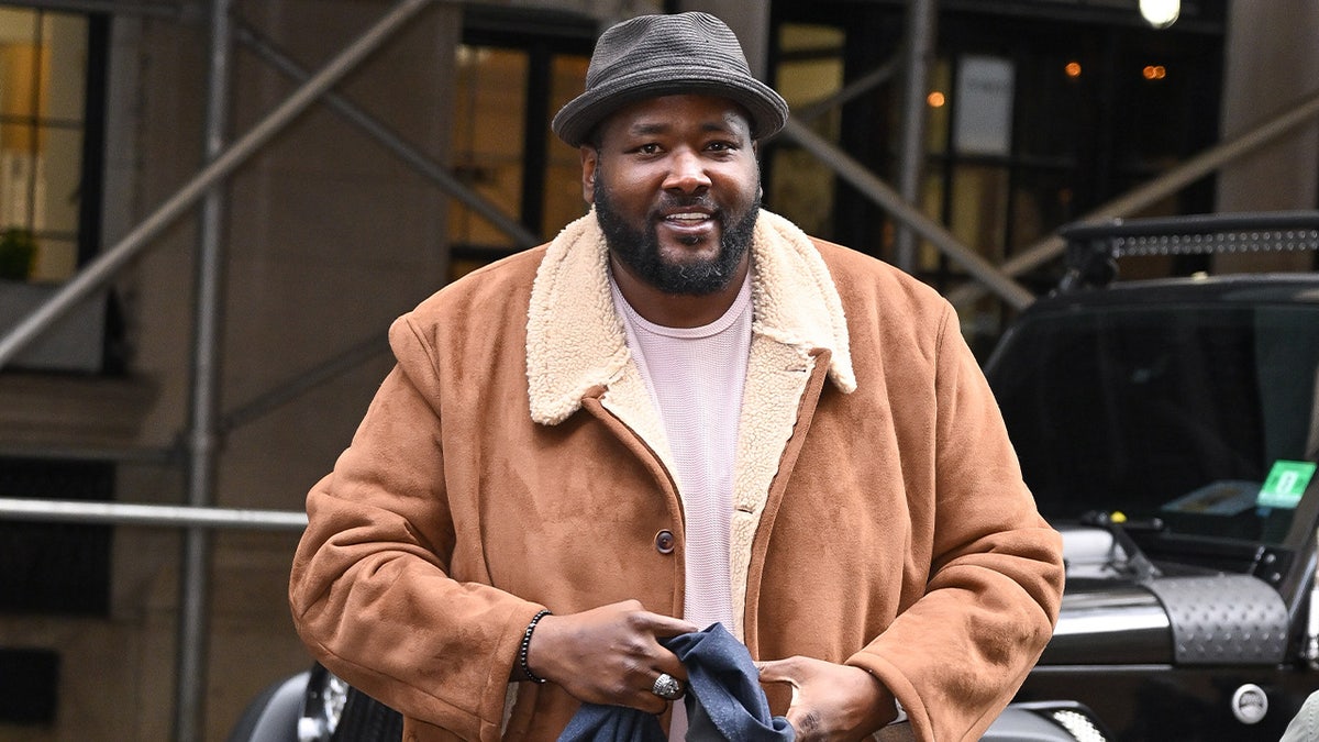 Quinton Aaron wears a coat and hat in New York