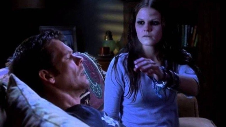 Tom Witzky sleeping on a couch while a ghost reaches out to him in Stir of Echoes