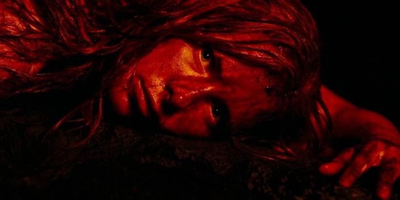 Shauna Macdonald as Sarah in the horror film, lying on the floor of a cave covered in blood in 'The Descent.'