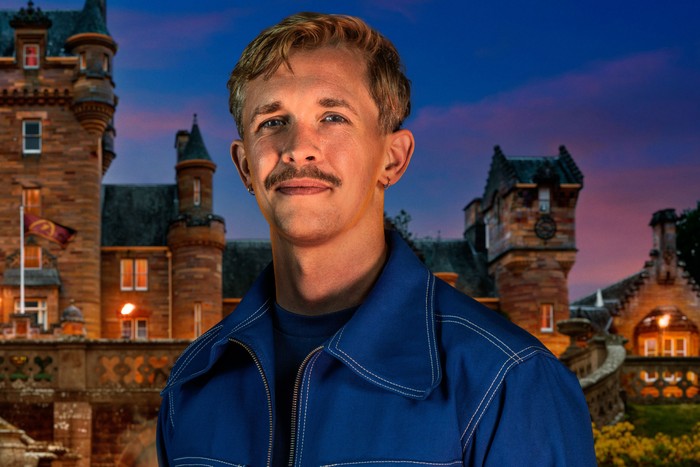 An image of a man smiling ahead wearing a dark blue denim jacket.