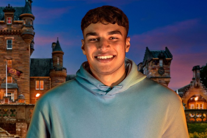 A man smiling and looking ahead, wearing a light blue hoodie.