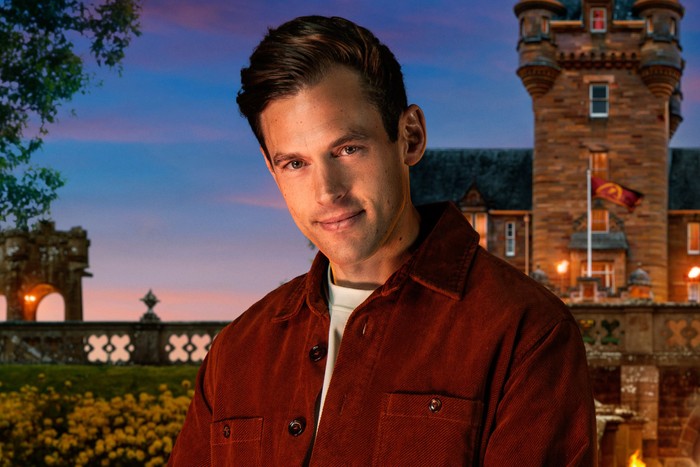 A man looking ahead with a charming smile, with his body slightly turned to the side.