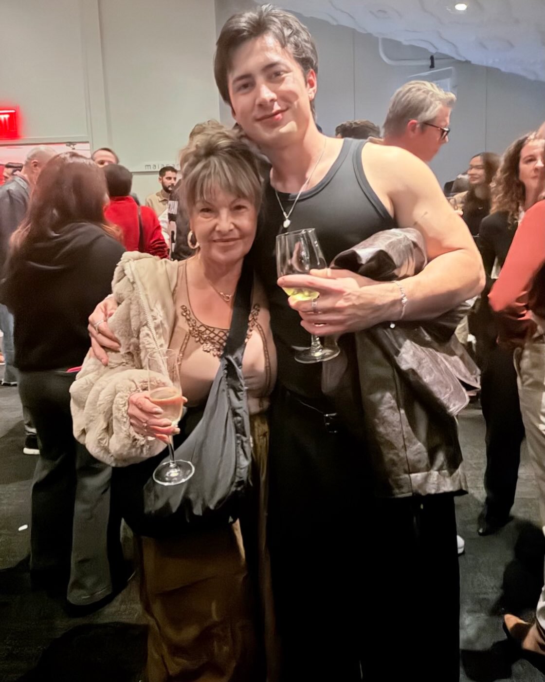 Hudson Williams with an older woman, both holding glasses of wine.