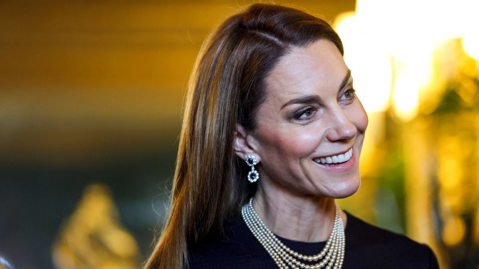 Princess Kate wearing a pearl necklace and sapphire earrings and smiling