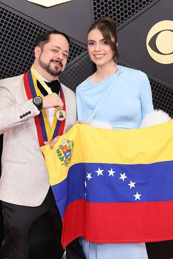 Raniero Palm holds a Venezuelan flag as he poses on the red carpet with Mariana Salas