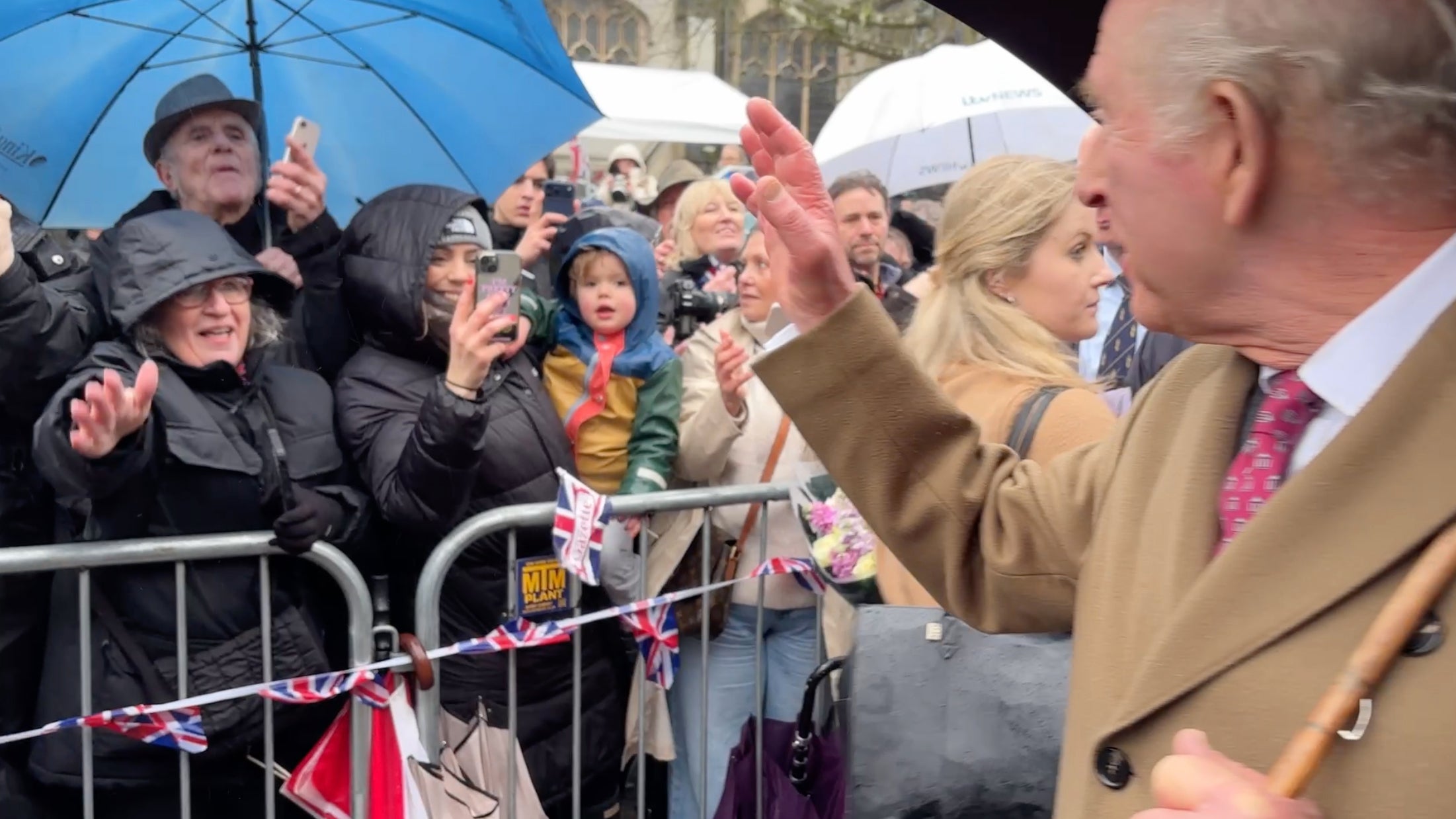 A heckler in a grey hat and holding a blue umbrella asked King Charles about Andrew's connection to Epstein