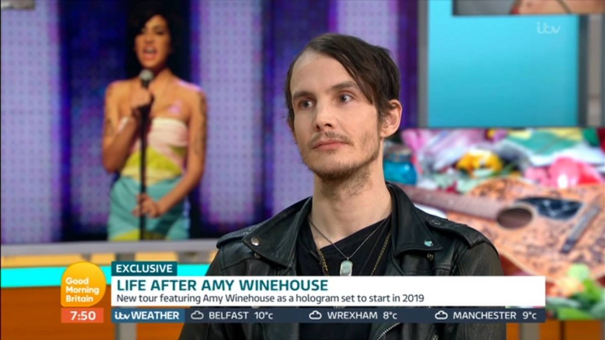 An individual with a serious expression, sporting a short haircut and a black shirt, positioned against a backdrop with a gradient of purple and blue hues, and assorted items in the background.
