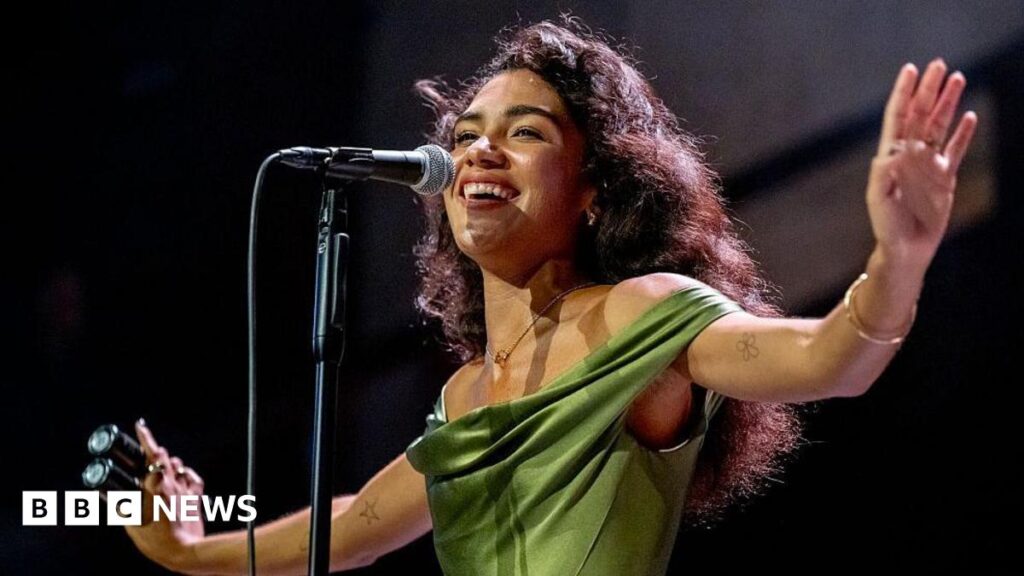 Olivia Dean stretches her arms out while she sings at Manchester's Albert Hall