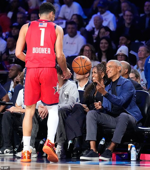Obama smiles after catching a ball during play next to USA Stars guard Devin Booker