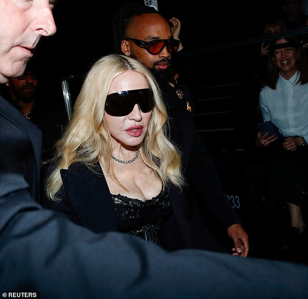 She paired the dress with sheer tights, an oversized black blazer, patent loafers and a pair of bright blue latex gloves