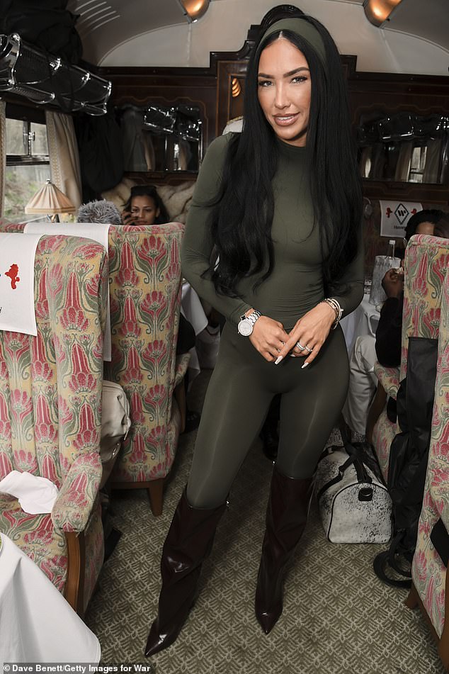 Underneath the jacket, Bre wore a khaki green skintight catsuit and matching headband, as well as knee-high patent black pointed boots