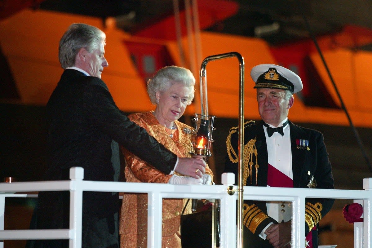 First Sea Lord Admiral Sir Alan West, right, looks on as Bruno Peek helps Britain's Queen Elizabeth II to light the Trafalgar Weekend Beacon during her visit to Nelson's flagship HMS Victory in Portsmouth in 2005 (PA)