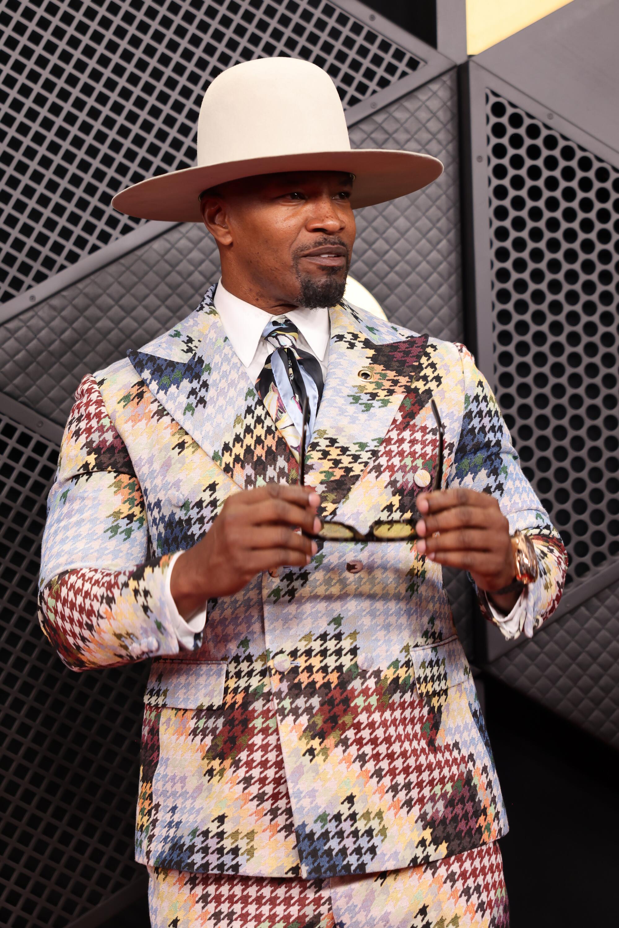 Jamie Foxx, wearing a patterned suit, poses on the red carpet. 