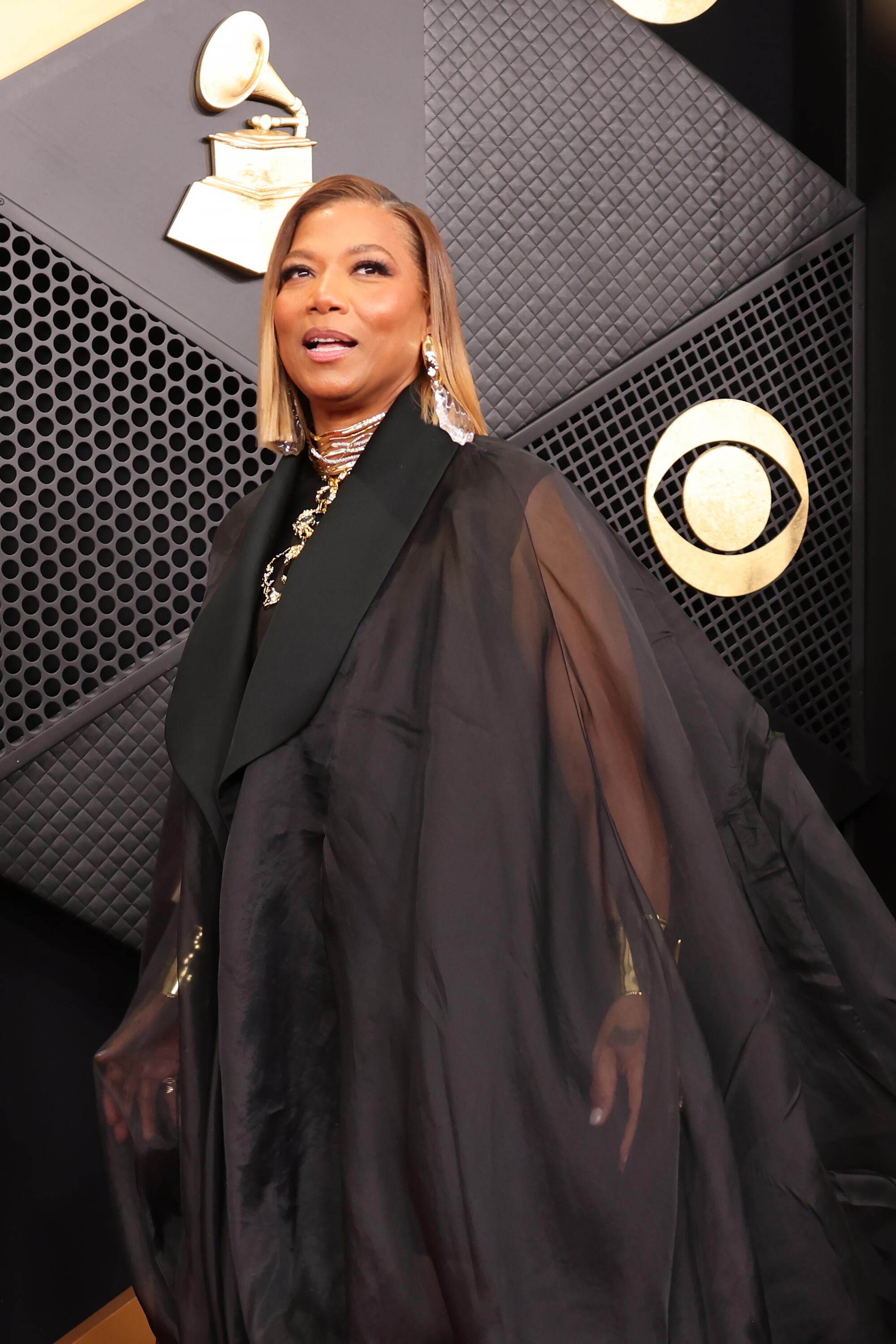 Queen Latifah, in a black cape gown, poses on the red carpet. 