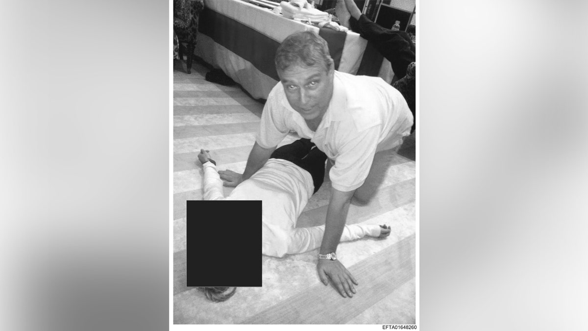 Andrew Mountbatten-Windsor looking at the camera as he kneels next to an unidentified woman.