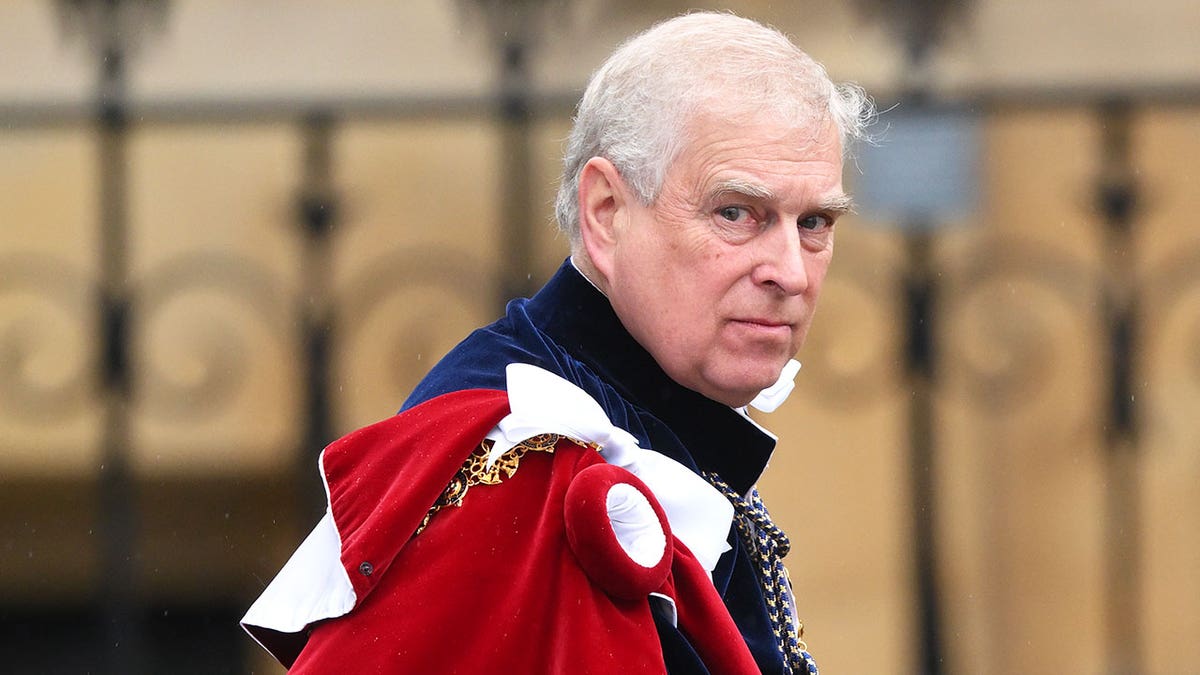 Ex-Prince Andrew in royal regalia looking upset as he walks outside.