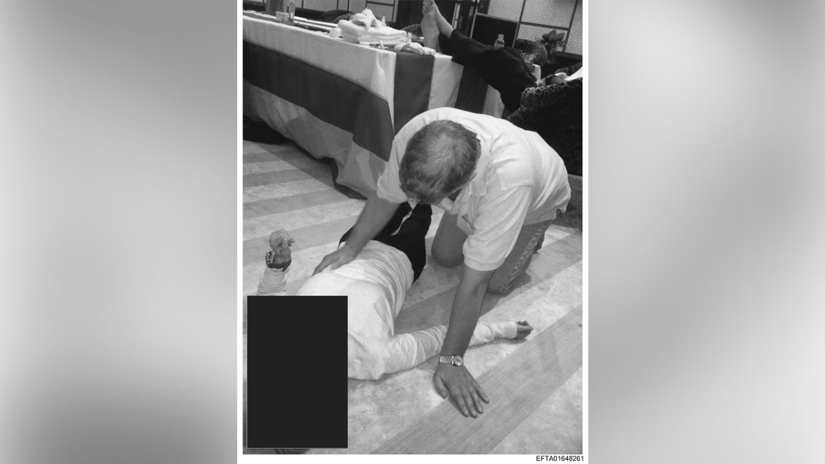 A black and white picture of Andrew Mountbatten-Windsor kneeling over an unidentified woman.