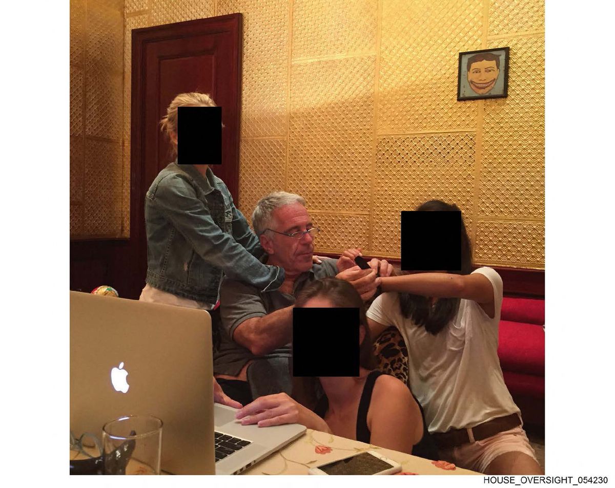 Jeffrey Epstein (2L) sitting next to women whose faces have been redacted.