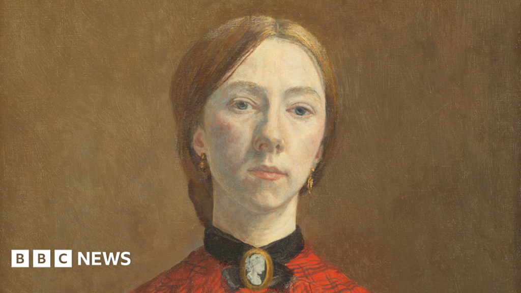 Oil painting of Gwen John. She is a white woman in her twenties. She has light red-brown hair pulled back into a low knot or bun at the back of her head. She is wearing an orange-red blouse with a check pattern on it. at her throat she is wearing a cameo broach with a black ribbon or collar around her throat. The clothing is consistent with the early 1900s. A black shawl is draped over her lower right arm.