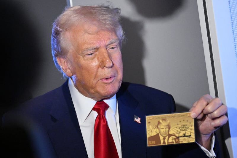President Donald Trump holds the Gold Card as he speaks to reporters while in flight on board Air Force One on April 3, 2025.