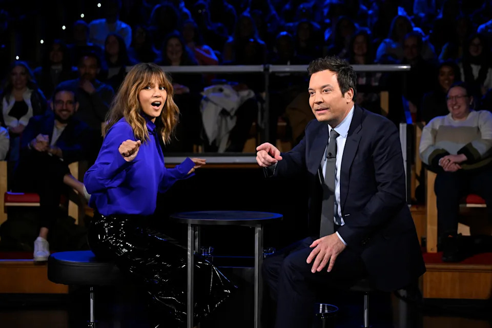 Halle Berry and Jimmy Fallon seated on stage looking out at a crowd during an interview on The Tonight Show, with an audience in the background