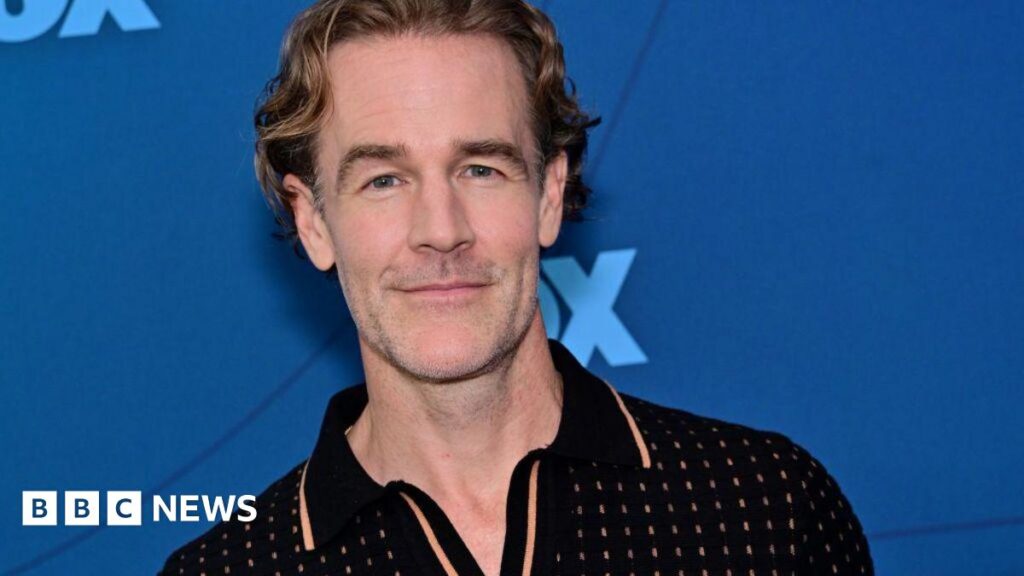 Why did former teen superstar James Van Der Beek need help to pay his medical bills? James Van Der Beek wears a black polo and stands in front of a blue background