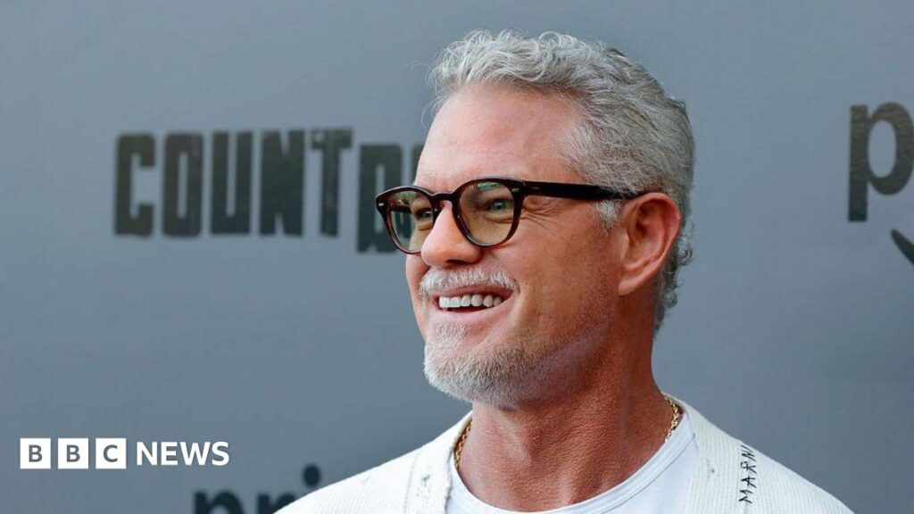 Eric Dane smiles and wears glasses