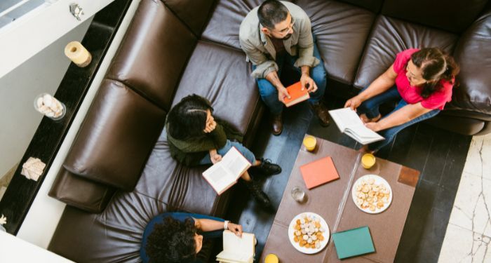 Two New Celebrity Book Clubs for 2026 Image of a group of people sitting around a table reading books