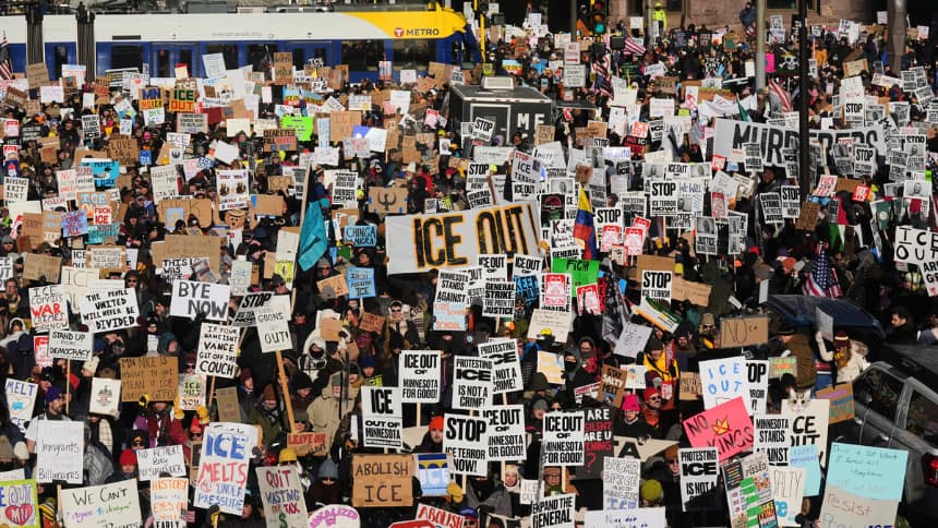 Thousands of protestors all holding ICE-related signs on a city street. 