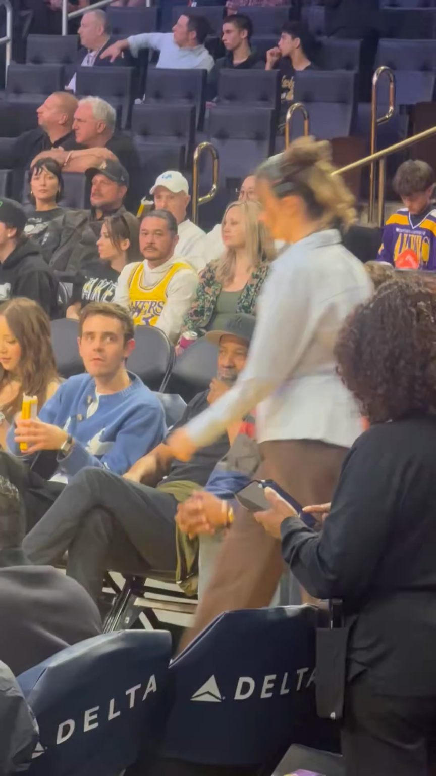 Denzel Washington casually walking across the basketball court to greet LeBron James