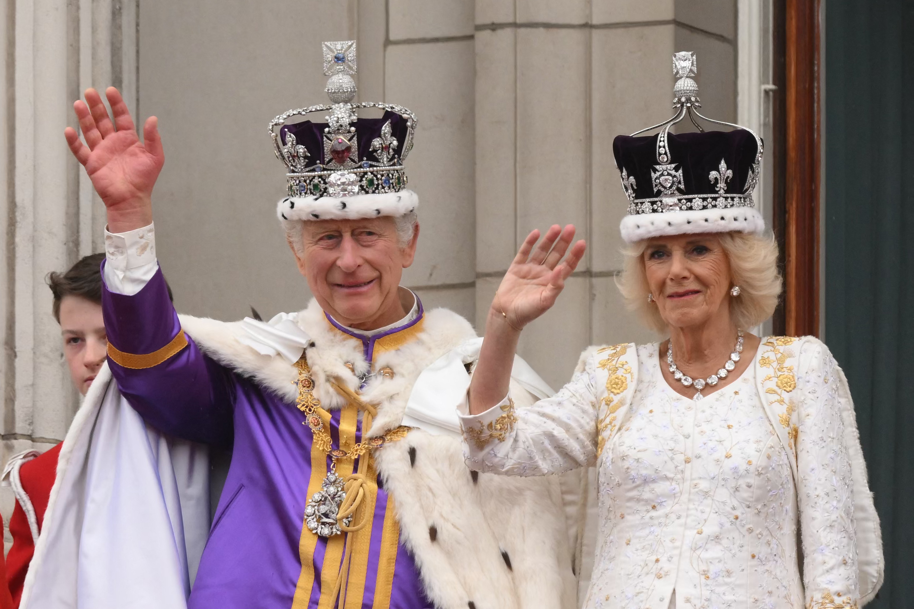 King Charles and Queen Camilla waving wearing crowns