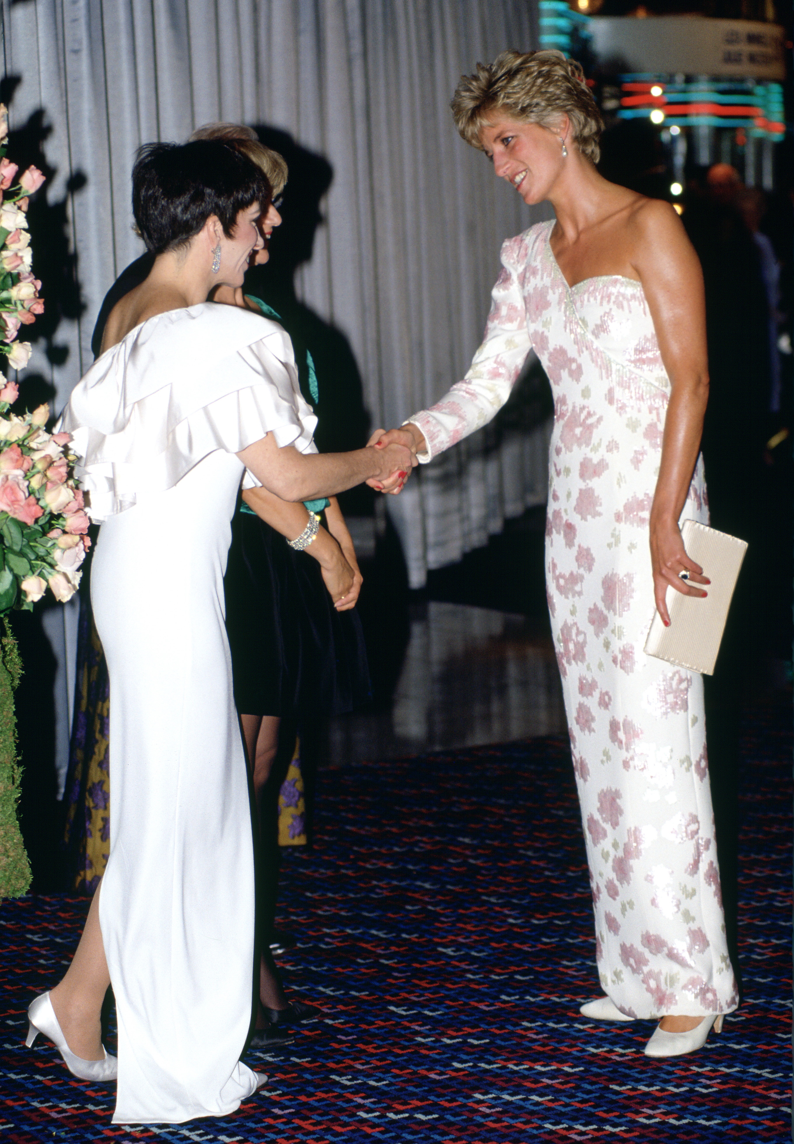 Princess Diana wearing a white gown shaking hands with Liza Minnelli