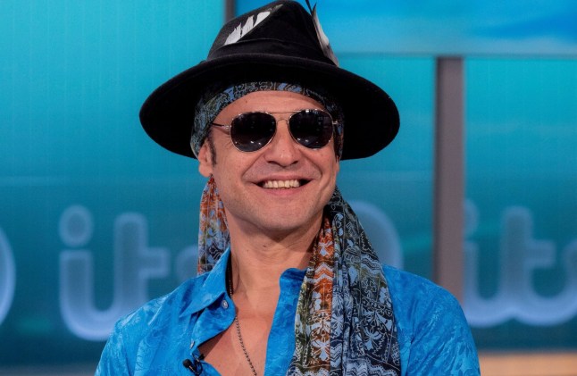 Chico Slimani smiling while on TV show Good Morning Britain, wearing sunglasses and a large hat.