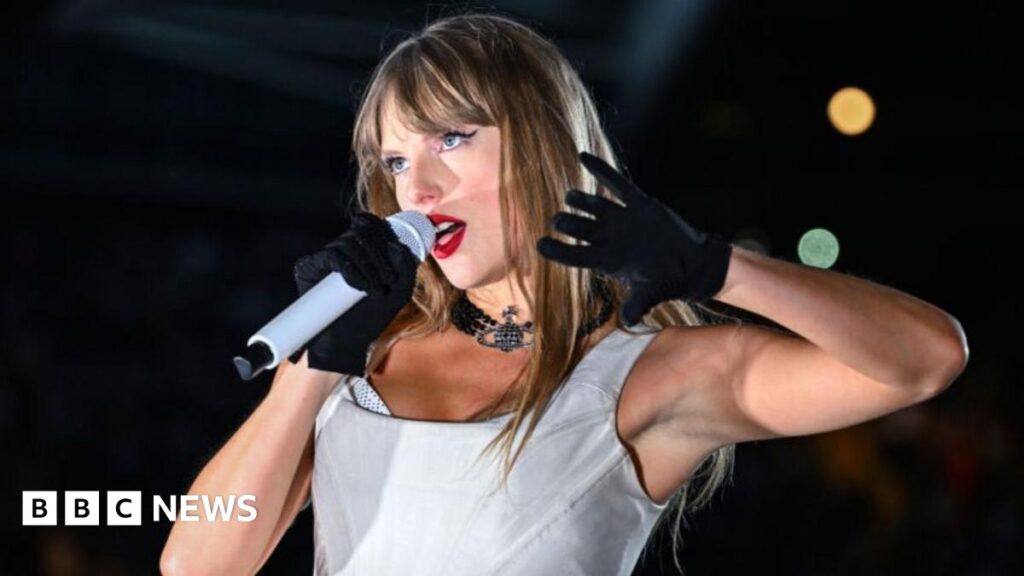 The image shows an elderly couple sat together in a dimly lit space, they both have bored expressions and are dressed in royal blue ballroom dancing outfits.
