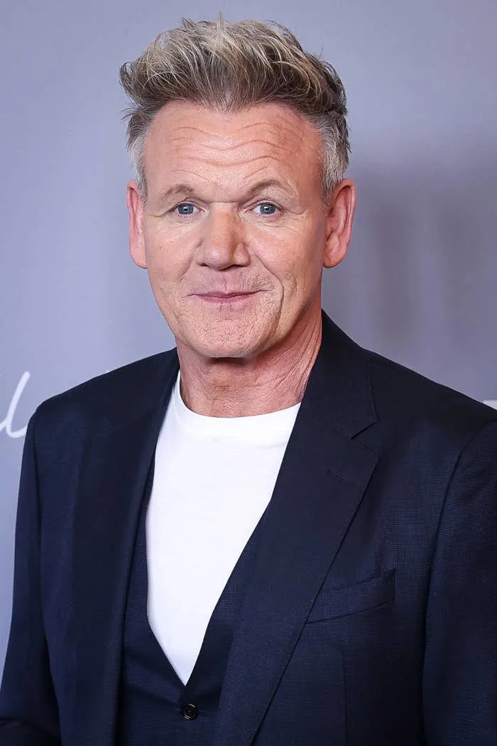 Person in a dark suit and white shirt at a formal event, smiling at the camera