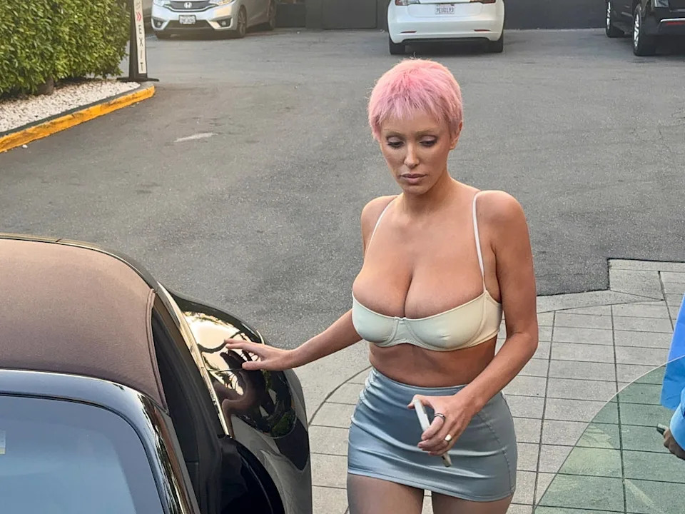 Person with short hair in a crop top and mini skirt opening a car door