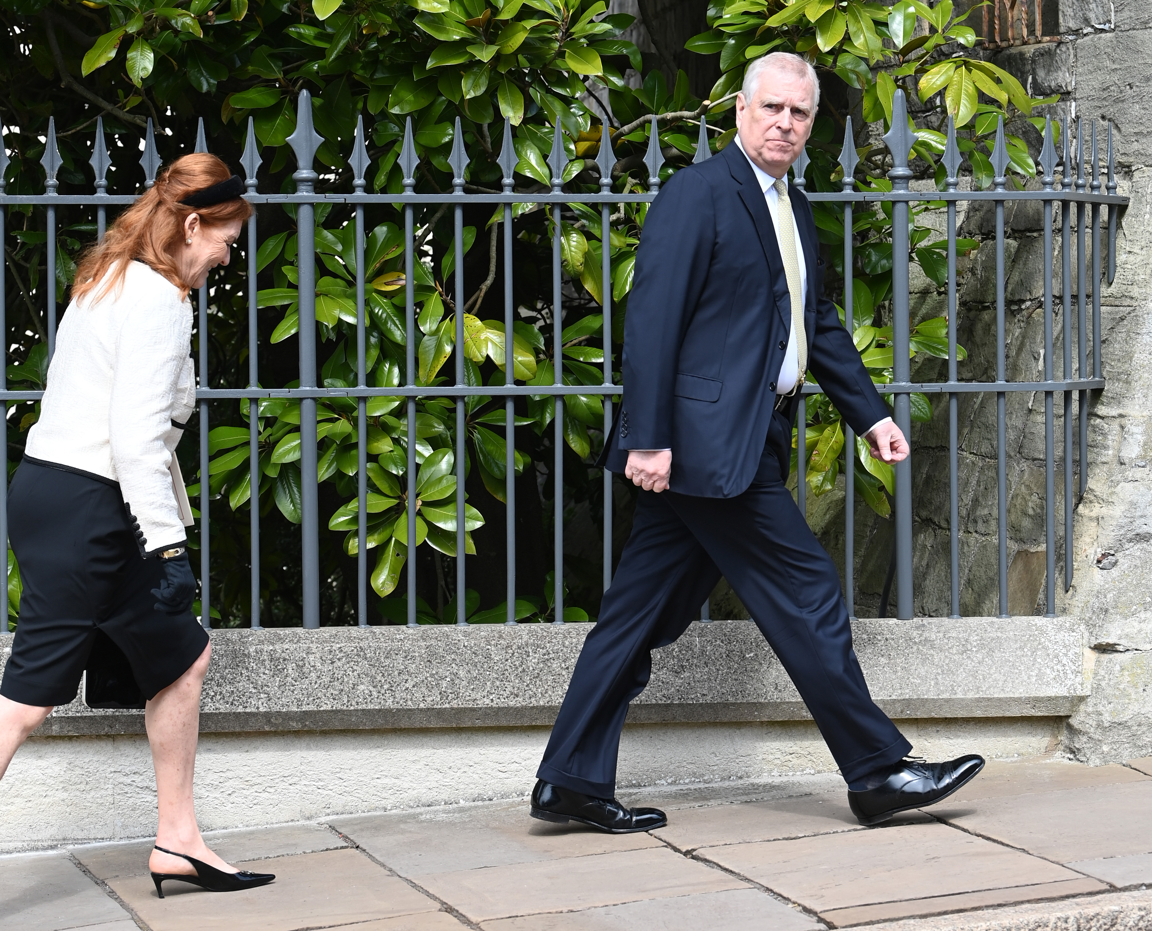 Sarah Ferguson walking behind Andrew Mountbatten-Windsor along a fence