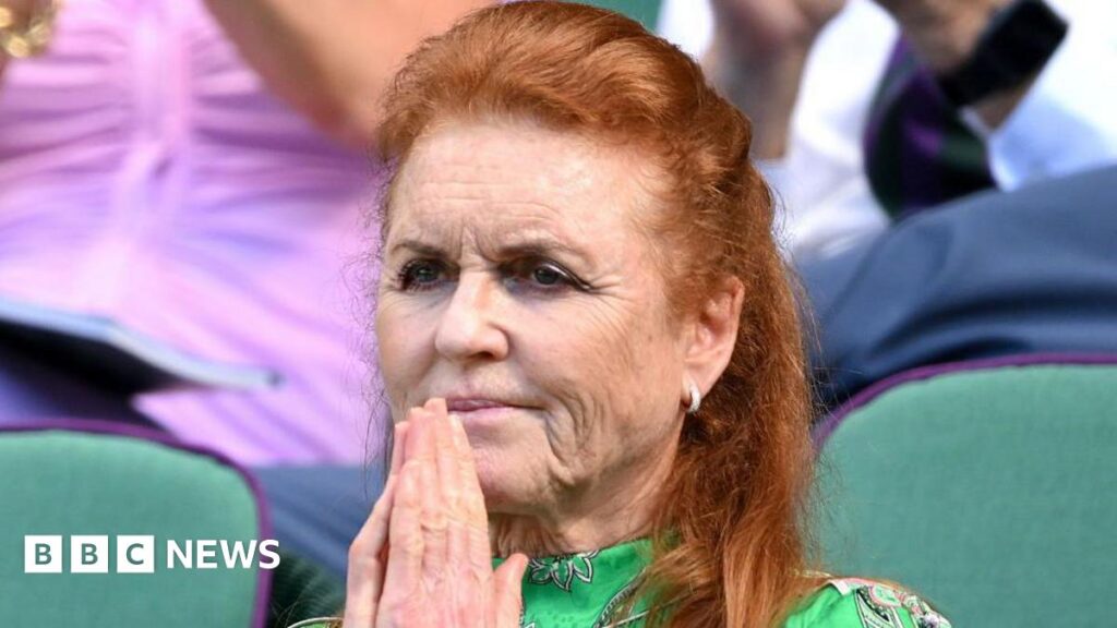 Sarah Ferguson sitting with her hands clasped in front of her face and a serious expression. She has long red hair and is wearing a green floral dress