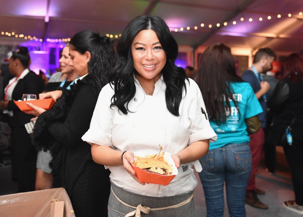 Chef Angie Mar, owner of The Beatrice Inn, holding a burger and fries.