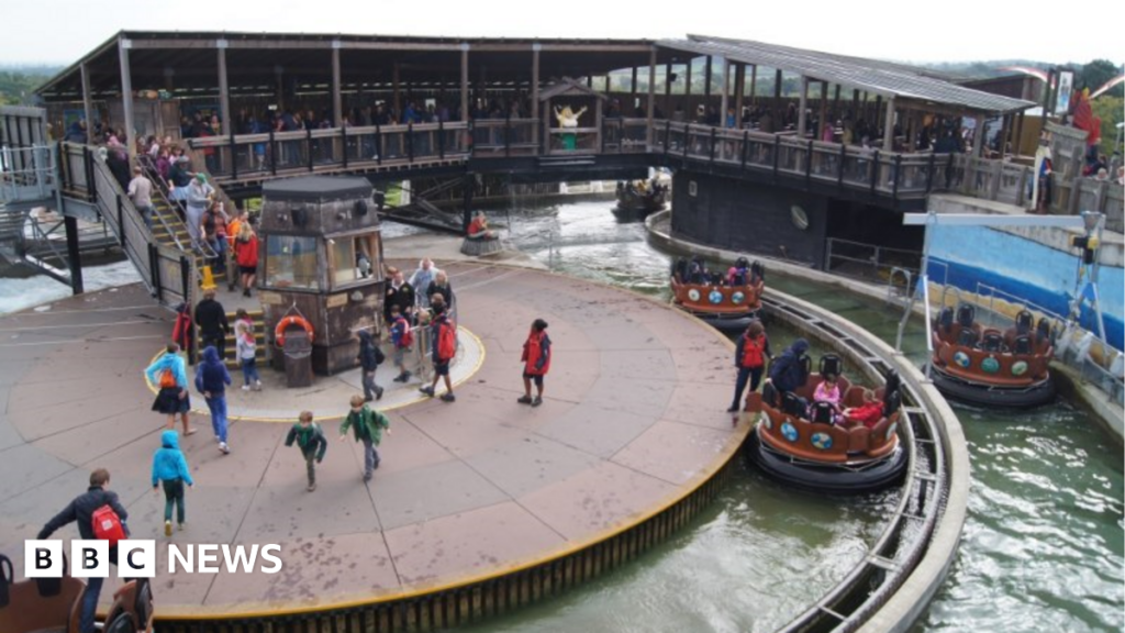 A picture of the rapids ride, with people on the ride itself and many people queuing in a covered area waiting for their turn.