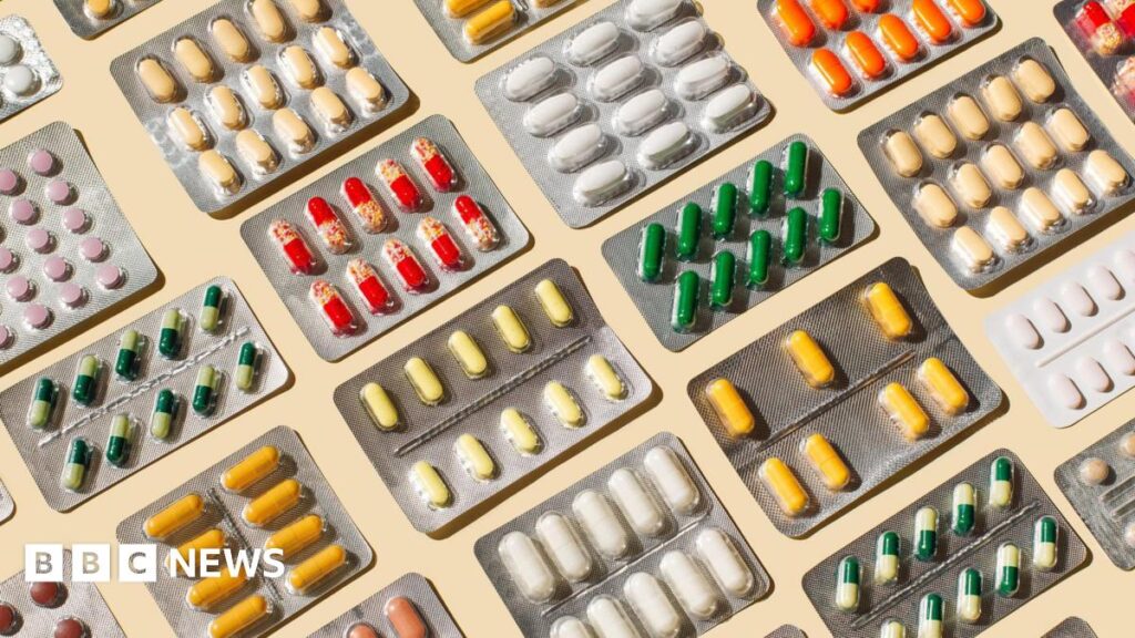 Pattern of blisters with colorful pills and capsules on beige background.