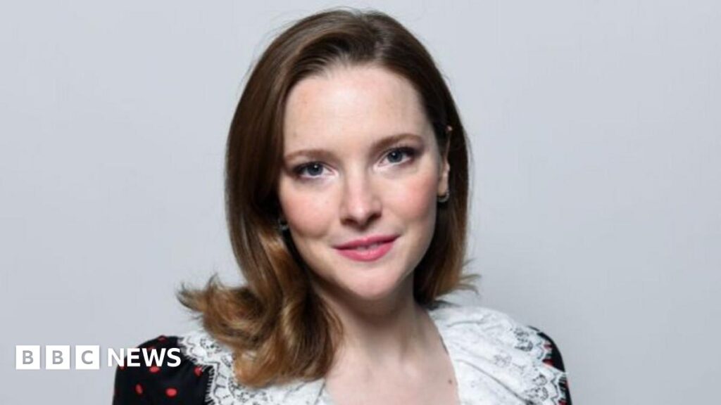 Lord of the Rings star cast as Lennon's wife in Beatles biopic – BBC Headshot of Morfydd. She has brunette hair and wears an off-shoulder black dress