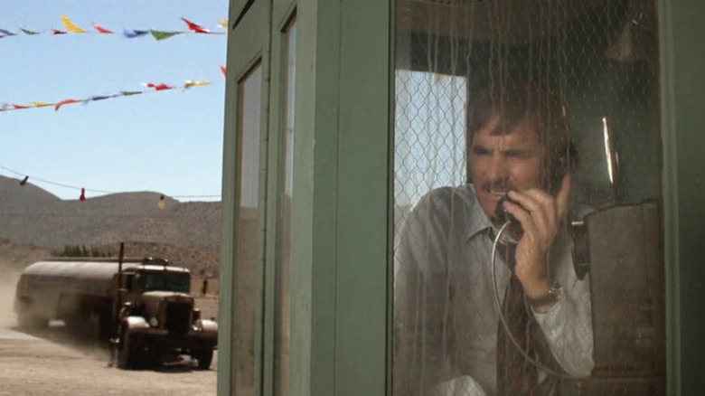 A tanker truck careens towards a phone booth as David Mann (Dennis Weaver) talks on the phone inside and unaware in Duel (1971)