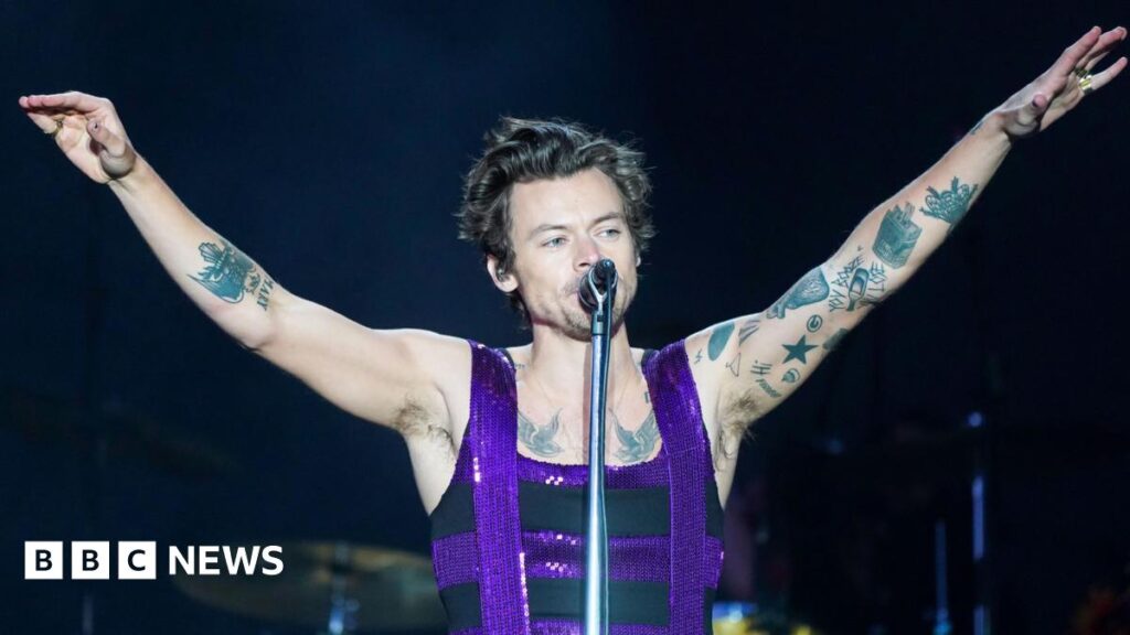 Harry Styles to play Manchester Co-op Live gig with £20 tickets Harry Styles in a purple sequinned and black vest and tattoos on both arms - with two birds on his chest - he holds his hands up in the air and sings into the microphone