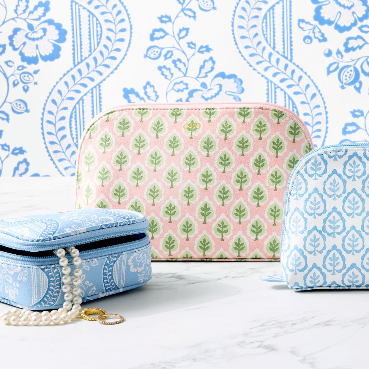 Cosmetic bags and a jewelry box with floral patterns on a marble surface.