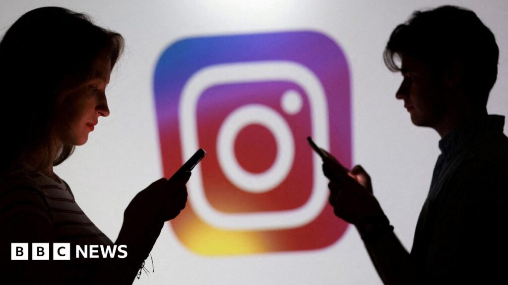 Disability charities warn of “fetishising” AI profiles on social media Two teenagers stand in front of a large logo of Instagram. Both are on their phones.