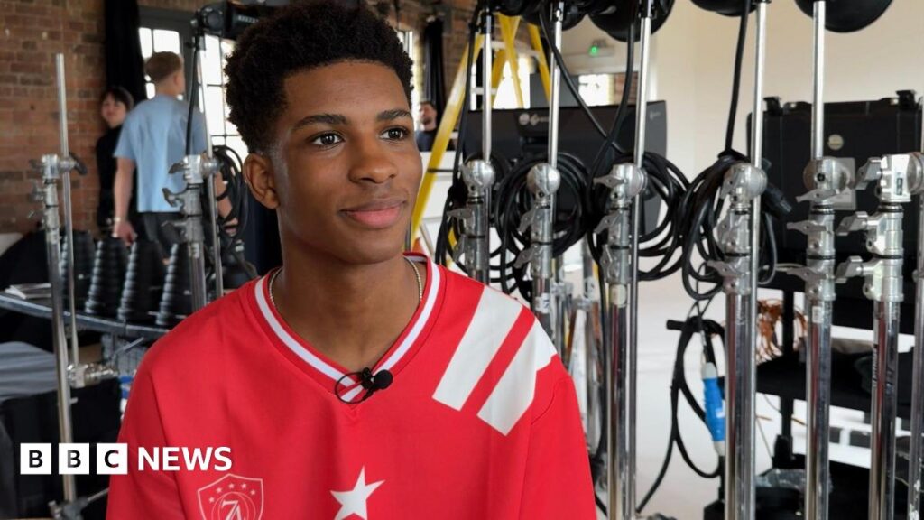 From Kent school chorister to Simon Cowell boy band A teenager wearing a red football shirt surrounded by microphones in a studio